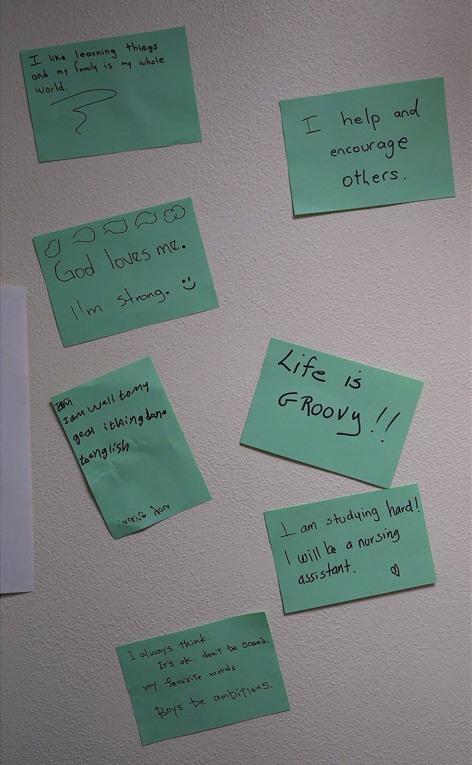 Green notes on a wall include handwritten messages such as "I help and encourage others," "Life is GROOVY!!" and "I am studying hard!"