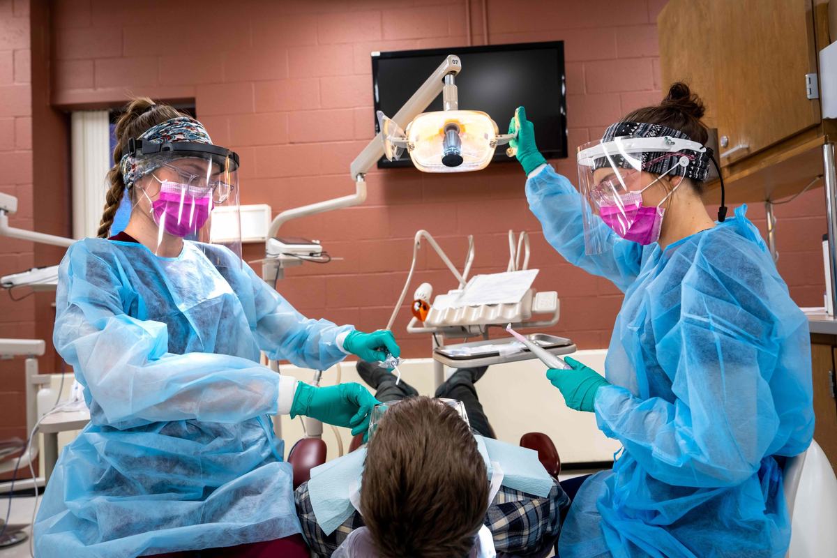 Two people in a dentist's office work on a patient