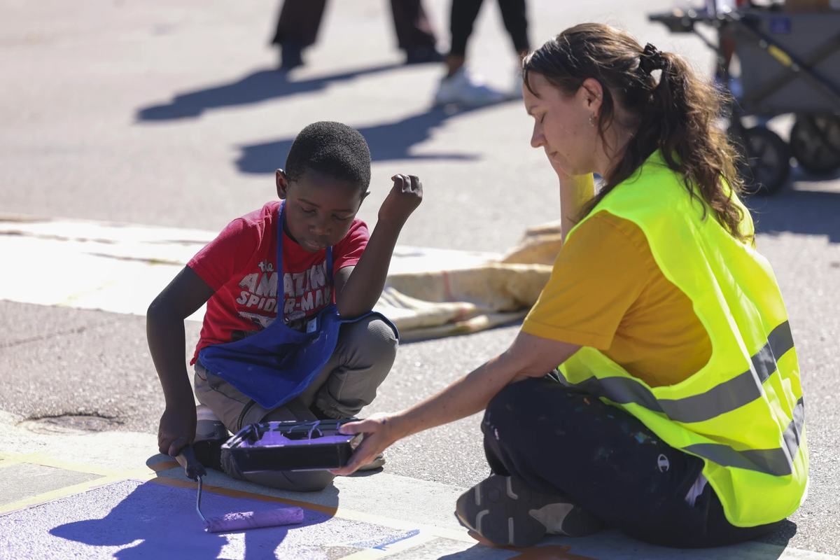 Tumelo Sampson, 6, helps paint a crosswalk mural with Christina Theobald.