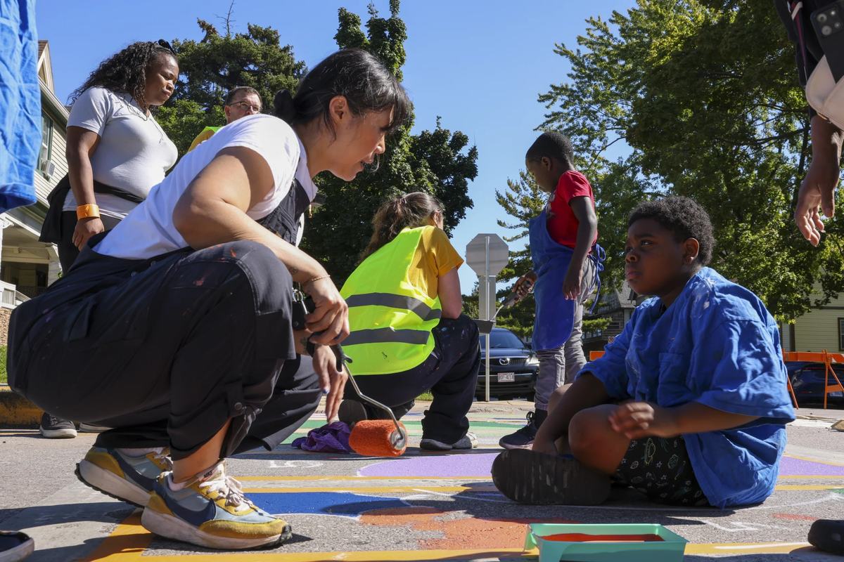 Local artist and designer of the mural, Emma Daisy Gertel, talks with Kayden Jacobs, 8, while painting.