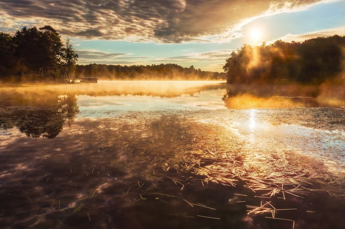 The sun rises on a scenic lake.