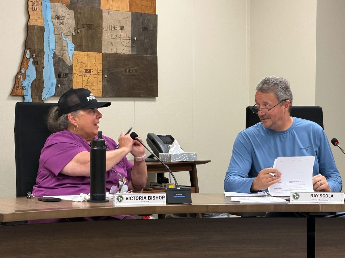 Two people sit side by side at a table during a meeting in a meeting room.