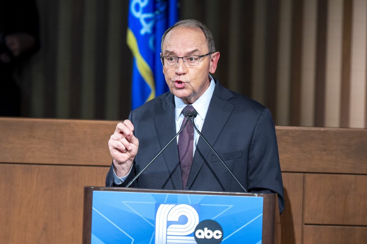 A man in a suit at a podium speaks