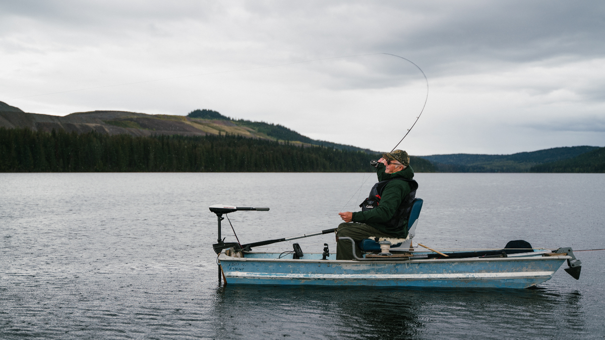 Man fishing on a boat in the water.