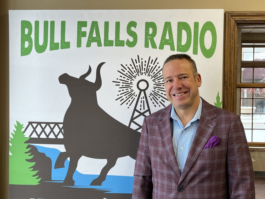 Sean Wright in front of the Bull Falls Radio logo