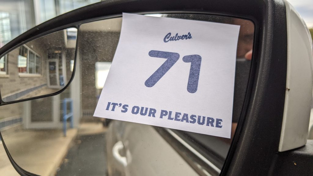 A sticker on a rearview mirror of a vehicle in a Culver's drive through.