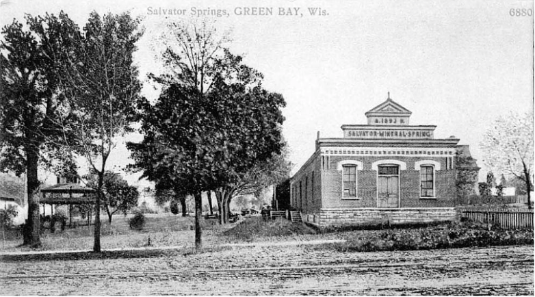 A vintage image shows a tree-lined dirt road beside a brick building labeled