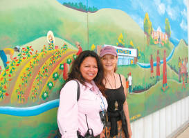 Gloria Reyes (left) with Sharon Kilfoy in front of a mural at Centro Hispano